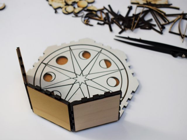 moon phase pattern cut into wood, with other pieces being attached as sides