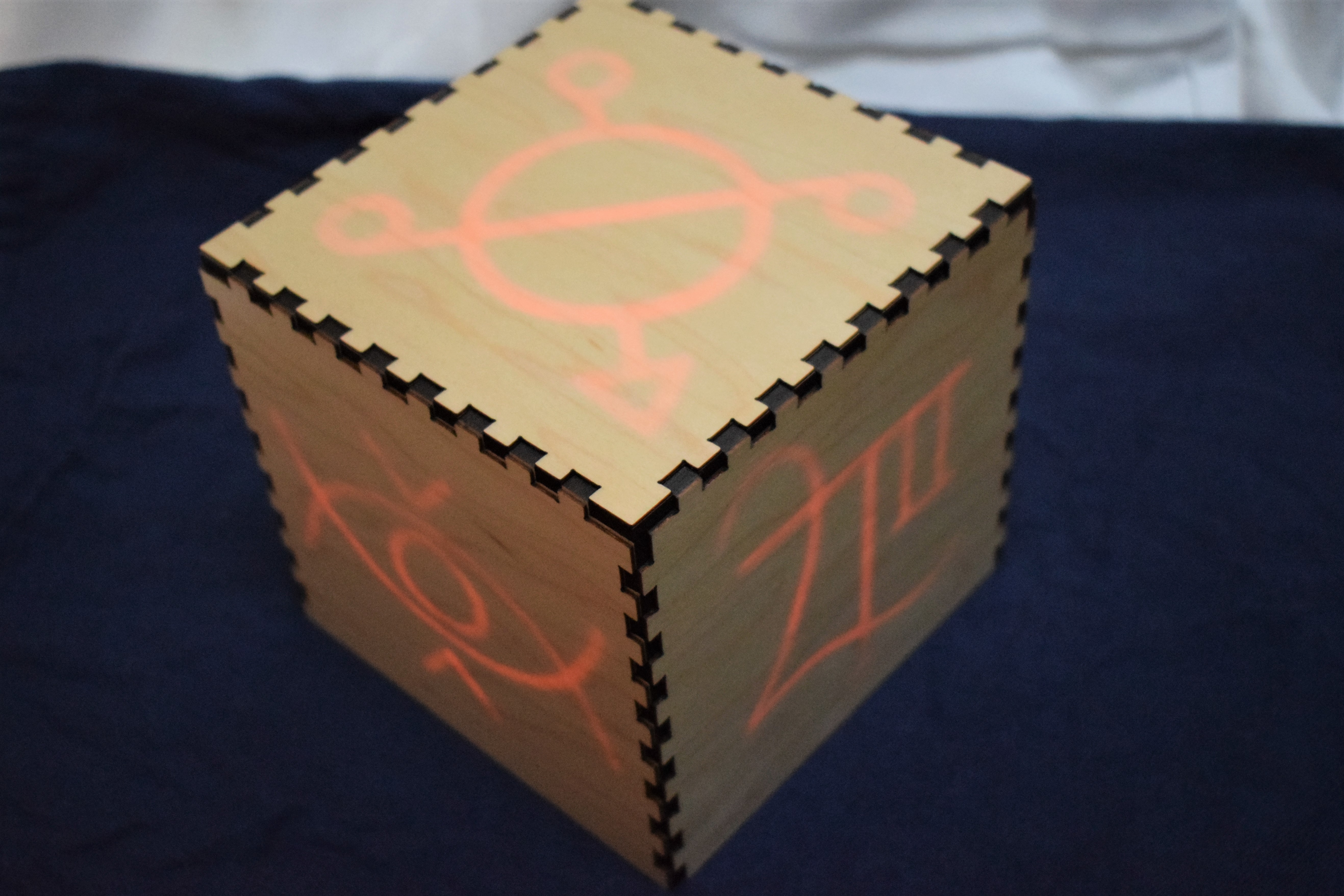 image of a plain wooden box that lights up with glowing red symbols when lit from within