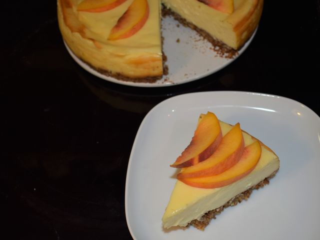 image of a slice of cheesecake topped with fresh peach slices